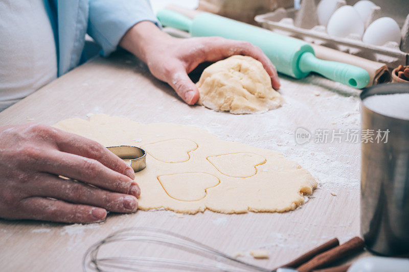 Girl making cookies in the shape of a heart in the kitchen, close-up. Surprise for your loved ones on Valentine's day, mother's Day or father's Day. Festive culinary background, with love